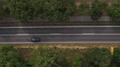 Top-view-of-traffic-on-road-through-country-landscape,-Aerial-shot-of-many-cars-driving-along-the-highway-through-nature-on-summer-day