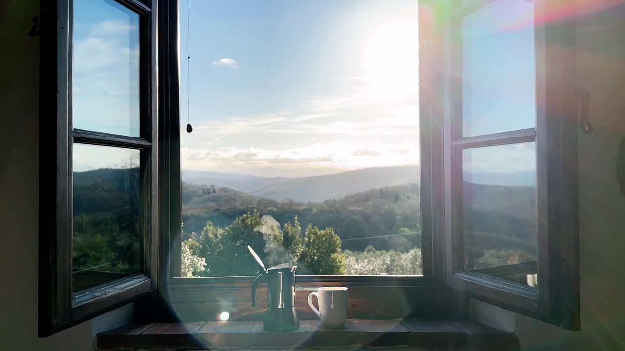 Hot espresso in a coffee maker with a cup on a window sill in the morning