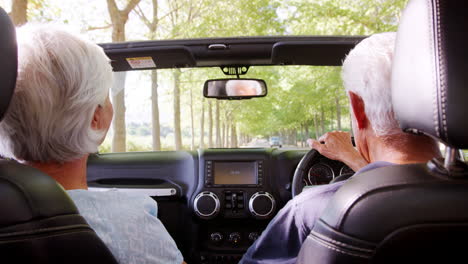 Punto-De-Vista-Del-Pasajero-Trasero-De-Una-Pareja-De-Ancianos-Conduciendo-Un-Auto-Descapotable