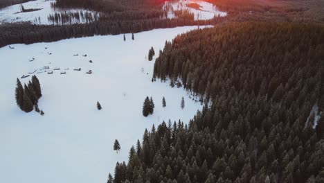 nature captured with a drone with the landscape, mountains covered in snow at golden hour at sunrise with  forest and surrounding hills captured in slovenia above forest pokljuka  above a village