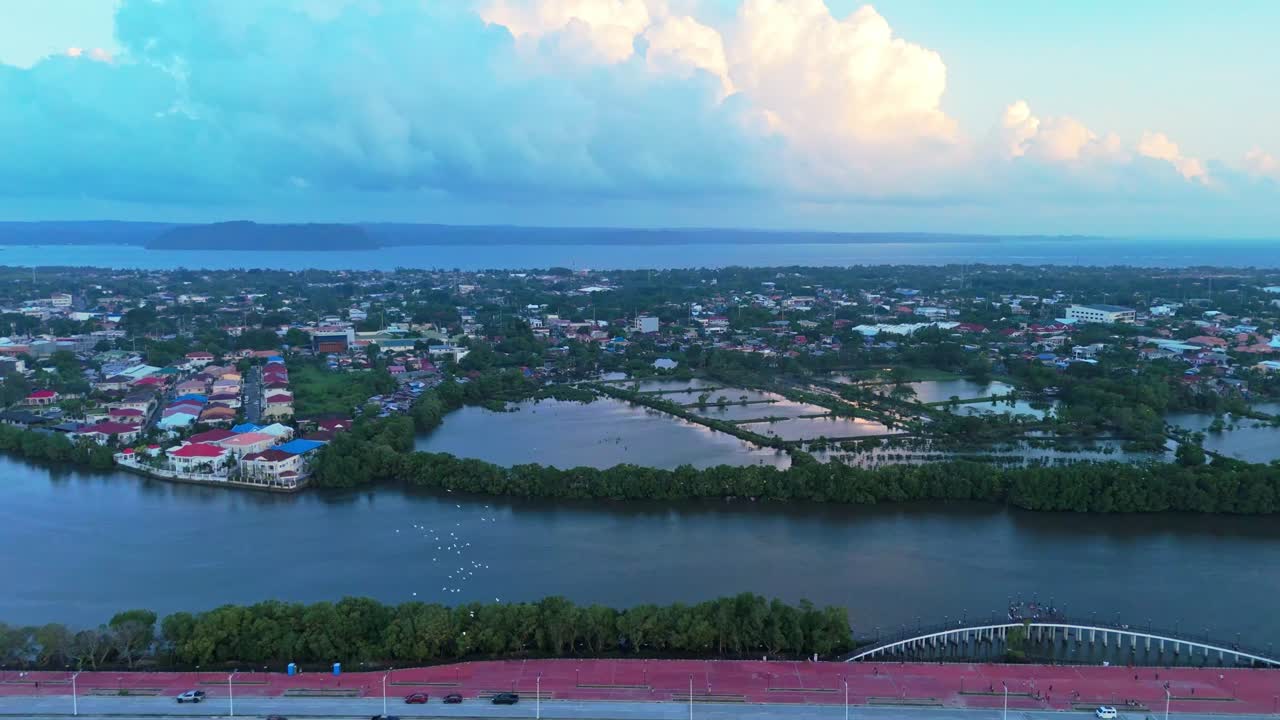 Drone footage of a Philippine cityscape with rivers, mangroves, and houses under dramatic clouds. Perfect for travel, lifestyle, and urban environment projects