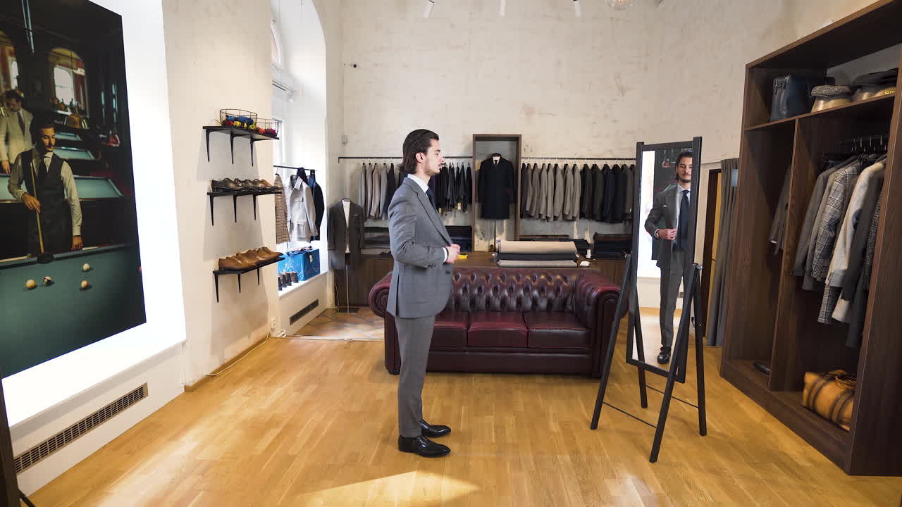 Ung mann sjekker seg i butikkens speil mens han prøver dress