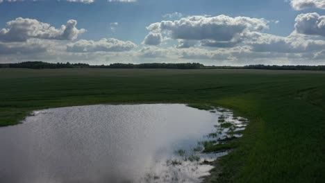 Ruhige-Landschaft-Mit-Teich-Und-Grünen-Feldern-Bei-Sonnenuntergang---Rückzug-Aus-Der-Luft