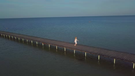 A girl walks on a wooden pier near the sea 01
