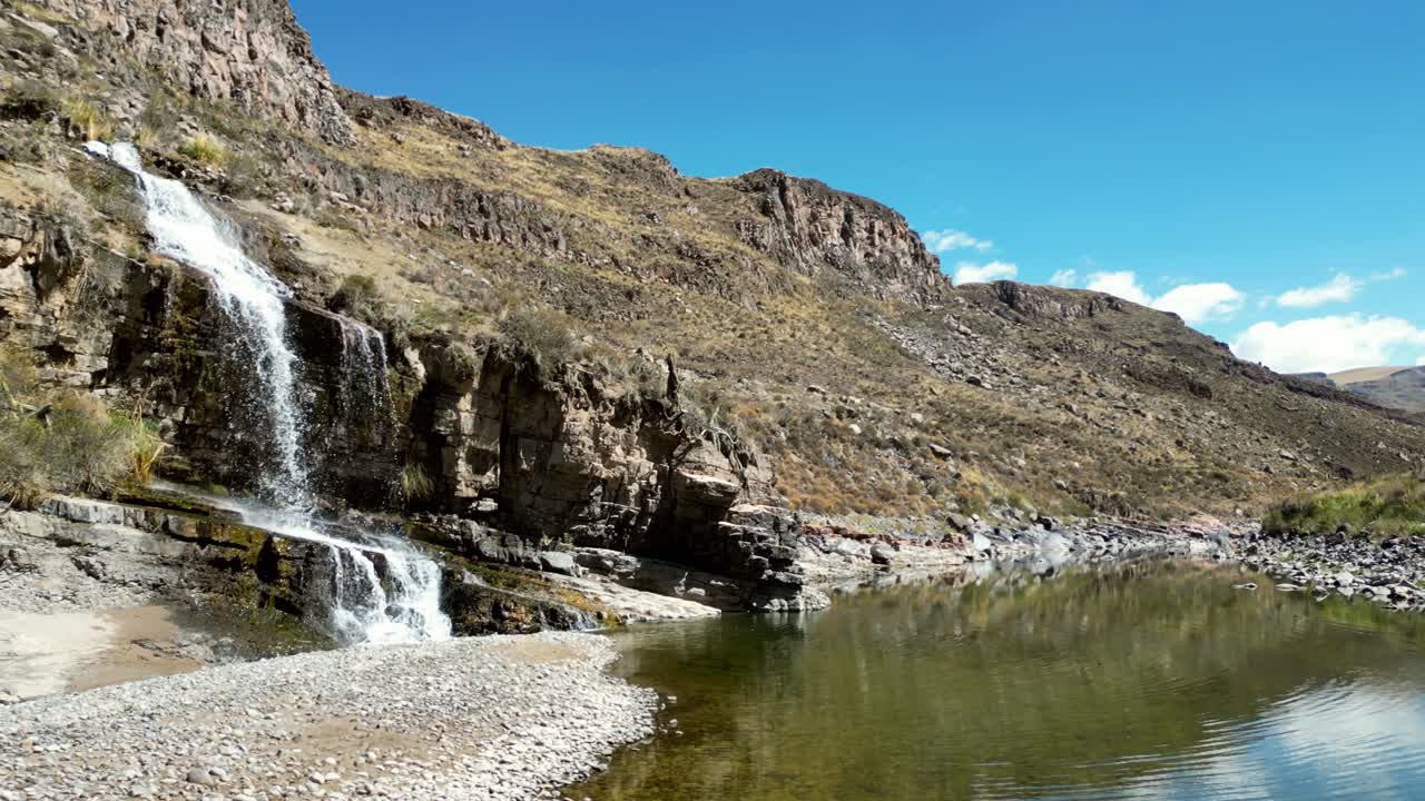 Drone shot tracing a river through a golden Andean valley. Blue skies mirror on the surface, merging earth and sky in perfect symmetry