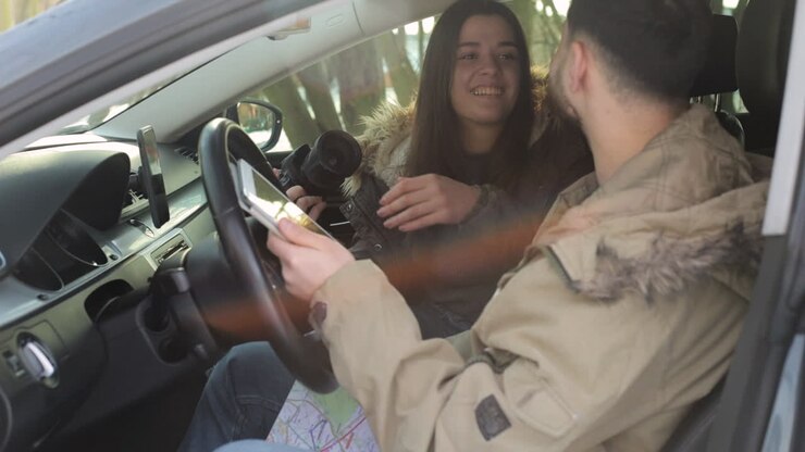 Coppia caucasica che si scatta foto a vicenda all'interno di un'auto e si bacia.