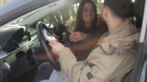 Caucasian-couple-taking-pictures-of-each-other-inside-a-car-and-kissing.