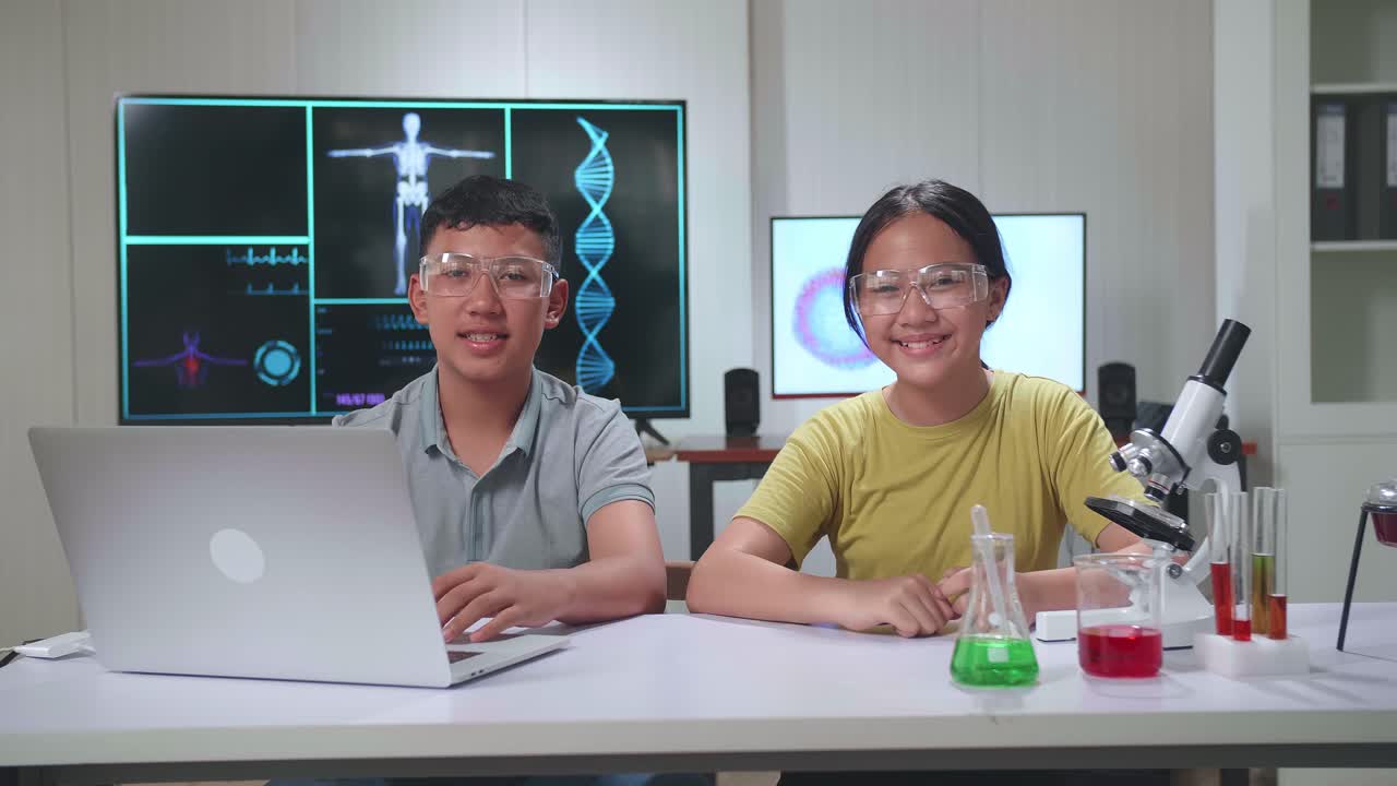 Young Asian Boy And Girl Smiling To Camera In Classroom. Study With Scientific Equipment. Education Concept