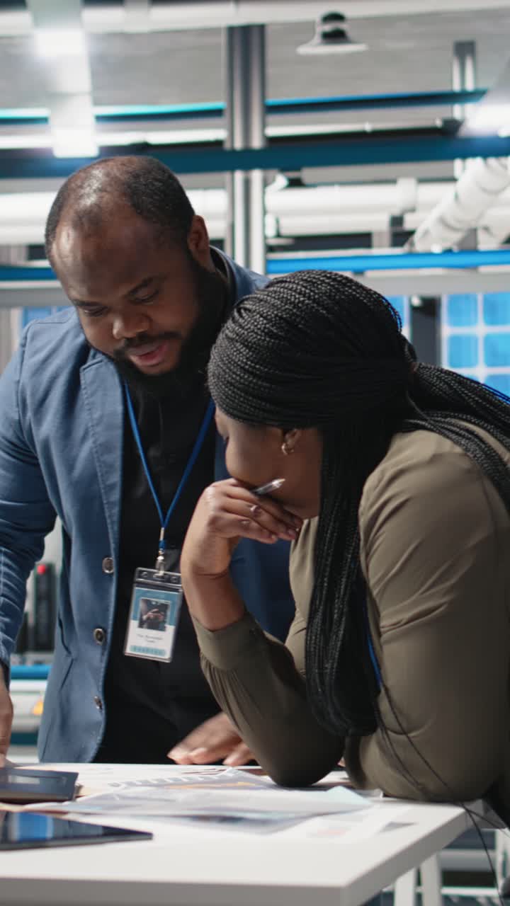 Vertical Video African american specialists supervisors examining production metrics on papers