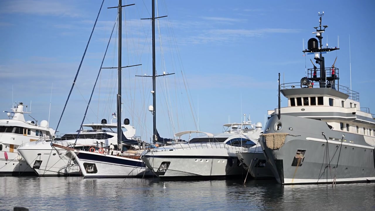 Collezione di yacht di lusso e motoscafi ormeggiati fianco a fianco nel porto turistico di Cannes sotto un cielo azzurro e limpido.
