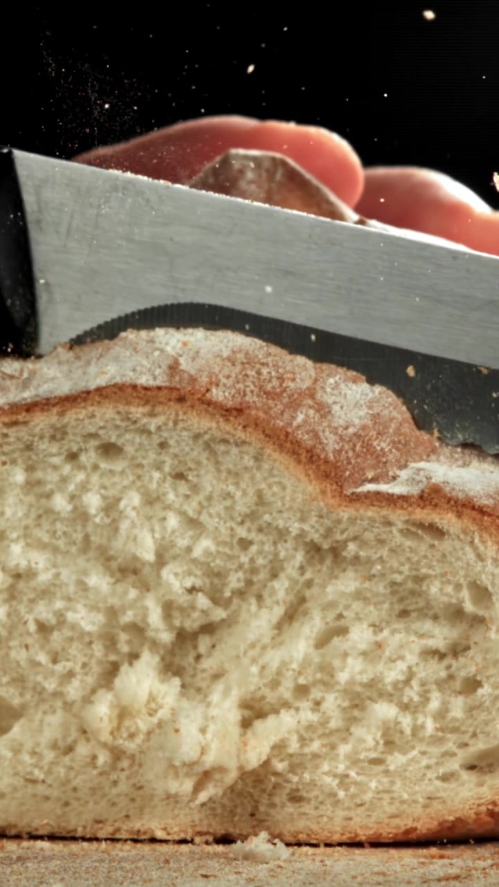 Slow Motion Close-up of a Knife Slicing Fresh Bread