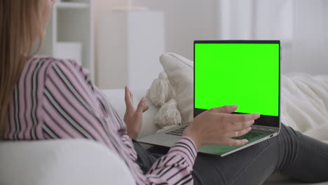 mujer alegre está usando llamada de video en la computadora portátil para comunicarse con un amigo pantalla verde en el portátil para la tecnología de clave de croma