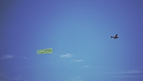 single engine plane flying in the air. small airplane towing advertisment banner