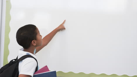 in school, young biracial male student pointing at something, copy space