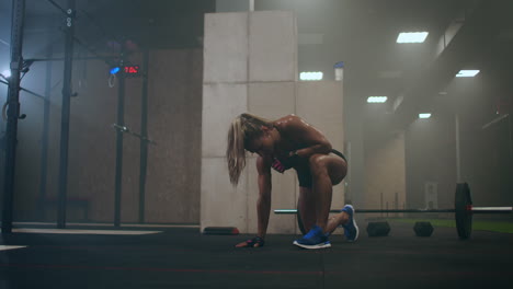 tired exhausted woman after a hard workout in the gym is sitting on the floor and breathing hard. professional athlete is preparing for competitions. hard work and the overcoming of itself and pain.