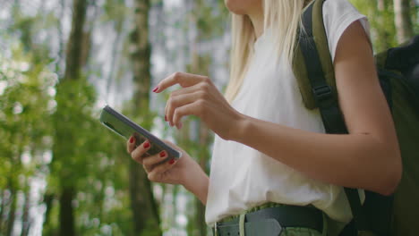 primer plano de un teléfono móvil en manos de una viajera caminando por el bosque. navegador y mensajero de redes sociales. use su teléfono móvil para un paseo por el bosque