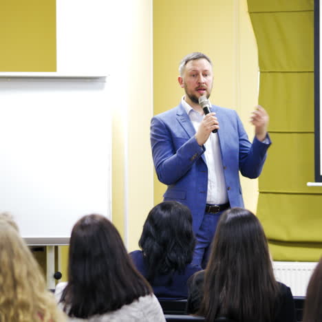 businessman explains new program to the audience. handsome man speaker conducts a lecture while standing near the white board in a conference hall.