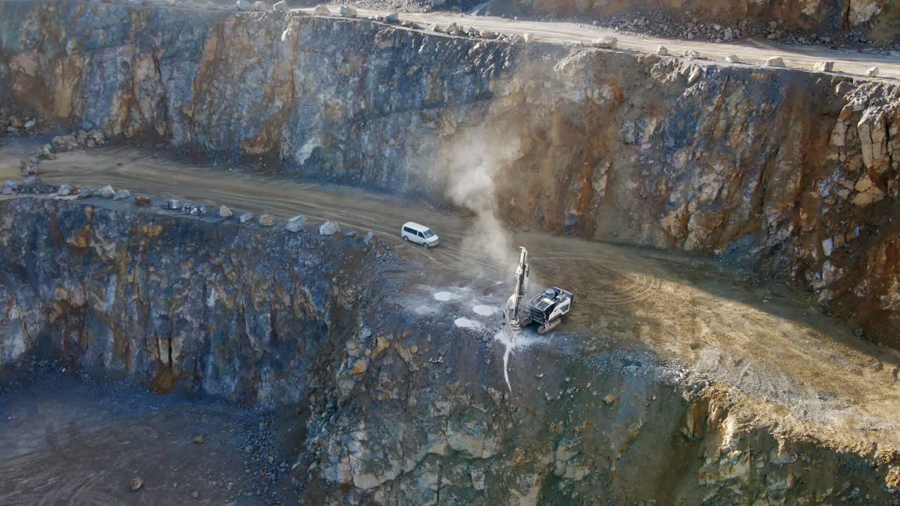 An Aerial View of a Track-mounted drilling rig drilling into rock to create holes for explosives in order to break up large rocks in a limestone quarry in Germany