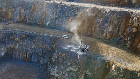 una vista aérea de una plataforma de perforación montada sobre orugas perforando rocas para crear agujeros para explosivos con el fin de romper rocas grandes en una cantera de piedra caliza en alemania