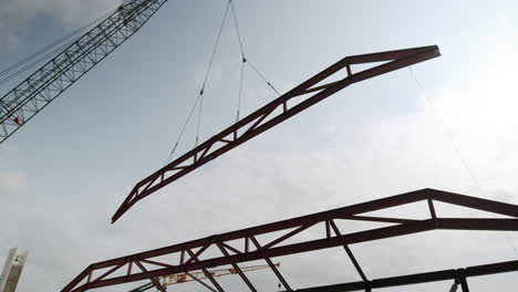 crane lifting a large steel truss during building construction