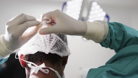 Back-of-african-american-female-doctor-wearing-face-mask-in-hospital-operating-room,-slow-motion