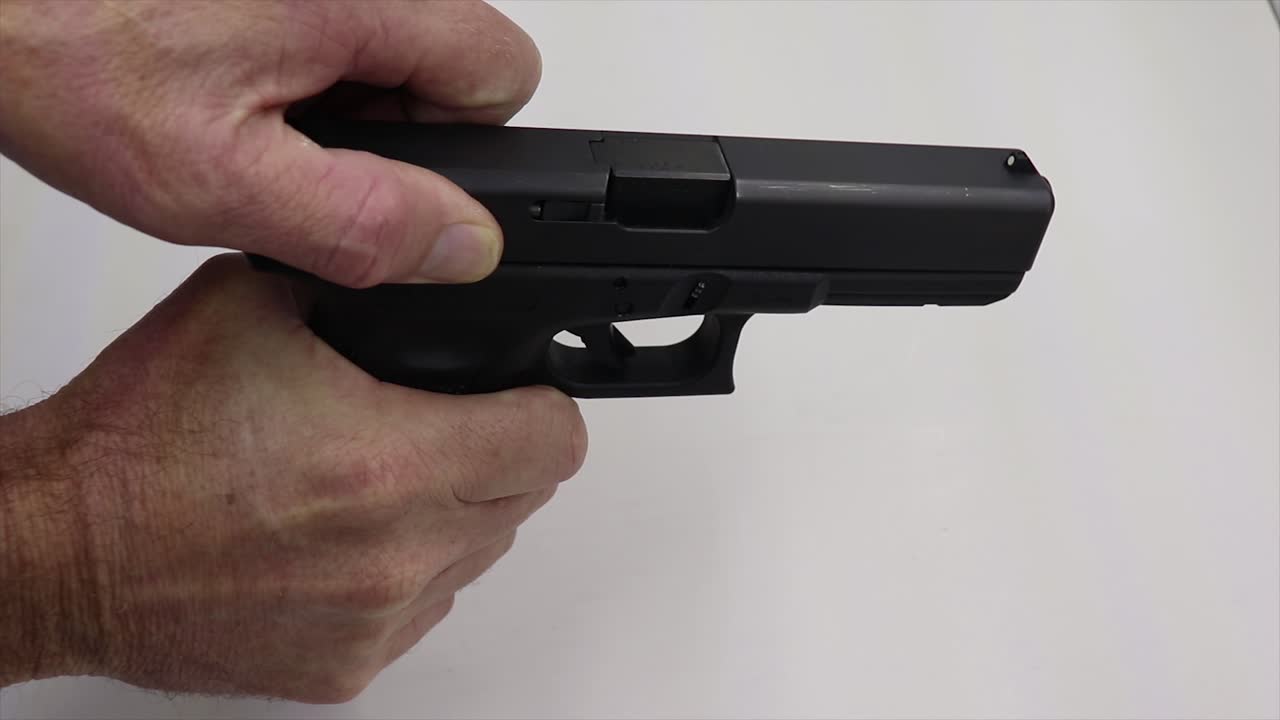 persona recogiendo un arma de fuego negra cargándola y alejándose dejando una mesa de balas