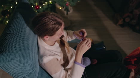 mujer tejiendo junto al árbol de navidad