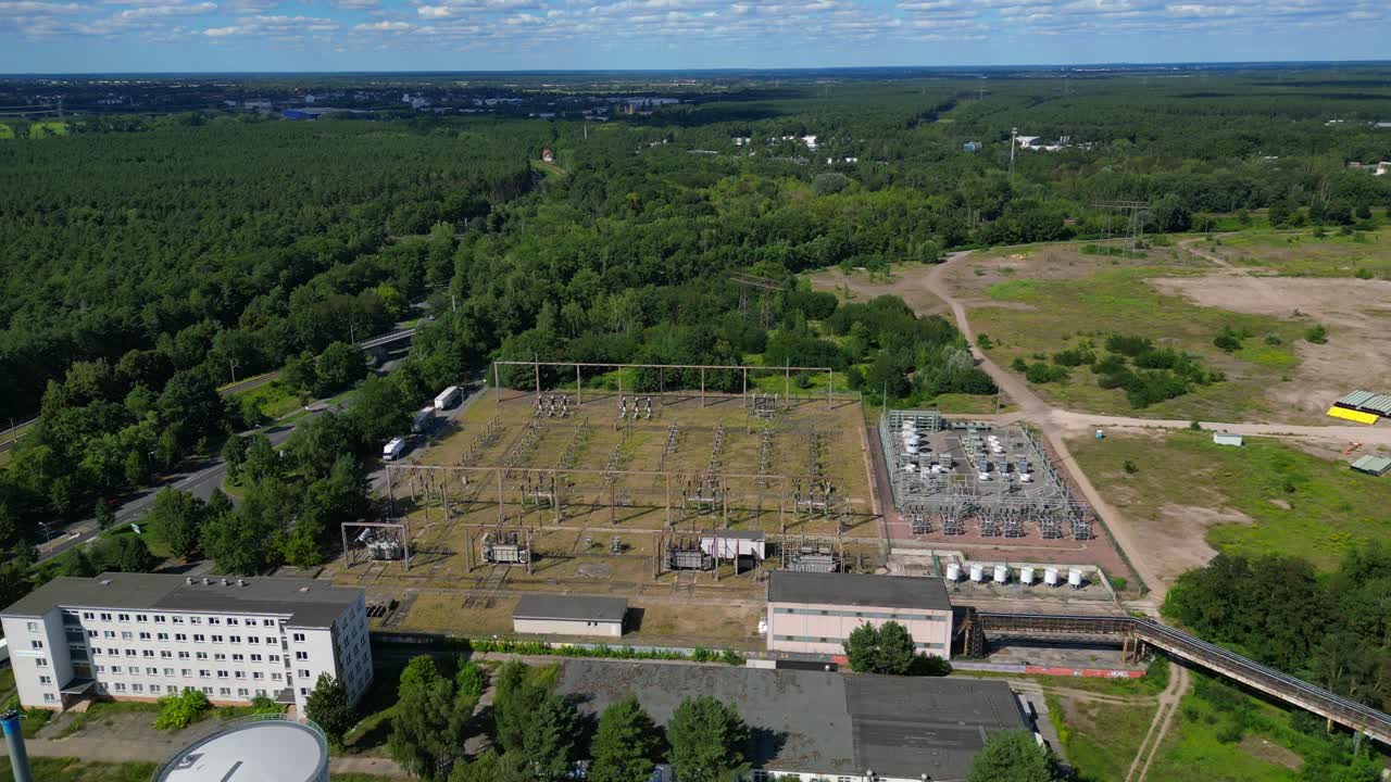 Hennigsdorf substation, distributing electricity and surrounded by a lush green forest in Brandenburg, Germany. Lovely aerial view flight drone shot from above
