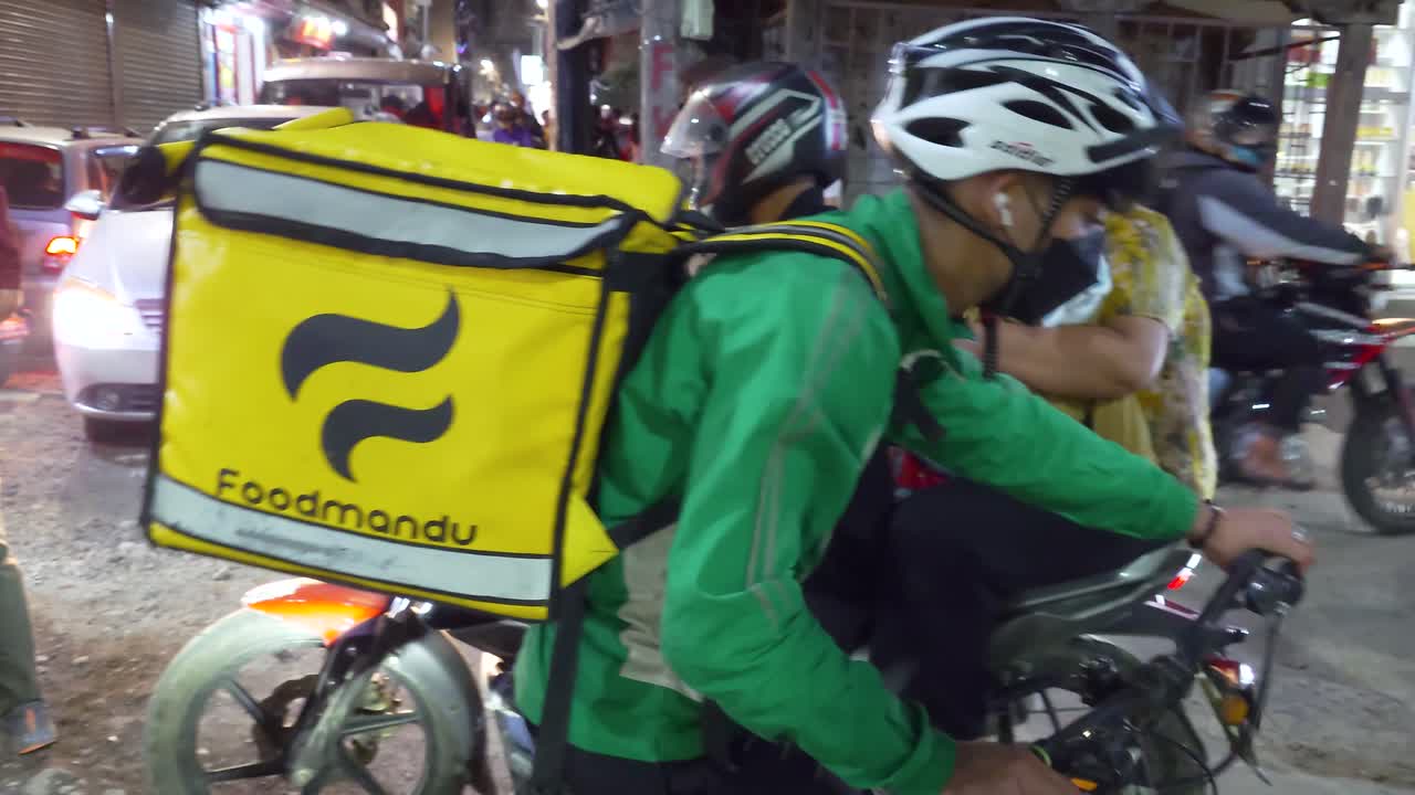 Foodmandu delivery rider cycling in the city center of Kathmandu. Online food delivery service in Nepal