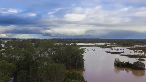 queensland, nsw, australia, inundaciones de febrero - dramático disparo aéreo de drones que viaja sobre matorrales inundados y sobre llanuras inundadas en brisbane, bajo cielos tormentosos dramáticos