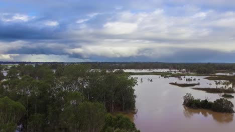 queensland, nsw, australia, february floods - dramatic aerial drone shot travelling over flooded bushland and over inundated flood plains in brisbane, under dramatic stromy skies