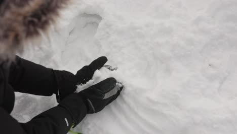 woman wearing gloves pick up snow in a winter environment