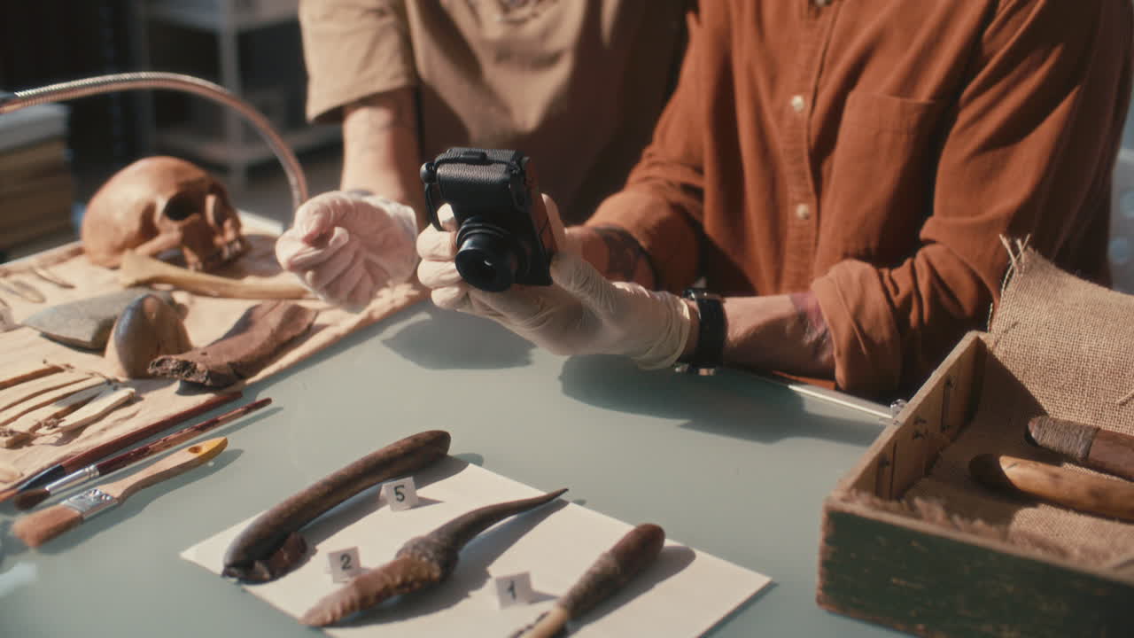 Two Archaeologists Documenting Ancient Artifacts with Camera in Laboratory