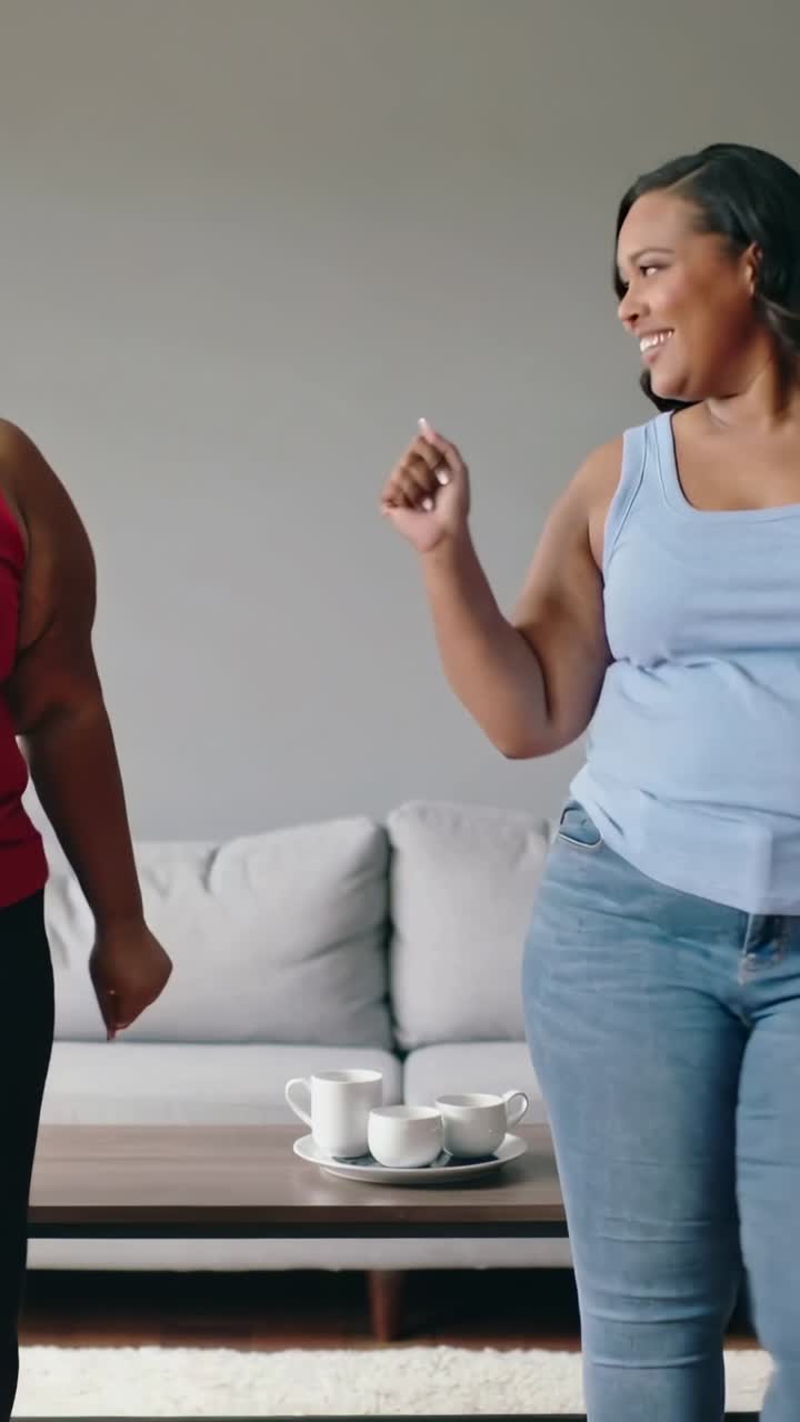 Dancing, friends facing each other wearing red and blue tops playing at home with cup tray