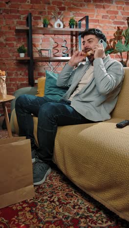 man eating fried chicken and talking on the phone