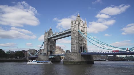 Traffic-under-and-over-Tower-Bridge-in-London,-boats,-cars-and-people-crossing-it,-day-view