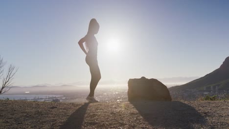 african american woman exercising outdoors stretching legs in countryside at sunset