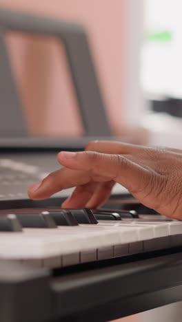 man hands on synthesizer keyboard closeup. black composer writes music on electrical instrument at home. african american guy learns to play