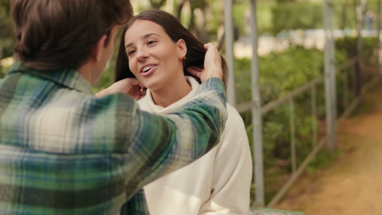 Close-up, happy young partners man and woman talking sitting in park