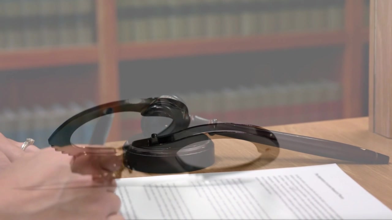 Esposas apareciendo, guiando manos que manipulan un documento en un escritorio legal con un mazo para la revisión de un caso.