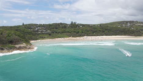 Menschen-Schwimmen-Und-Surfen-Im-Blauen-Meer---Rettungsschwimmer-Auf-Jetski-Patrouillieren-Am-Zylinderstrand-In-Qld,-Australien