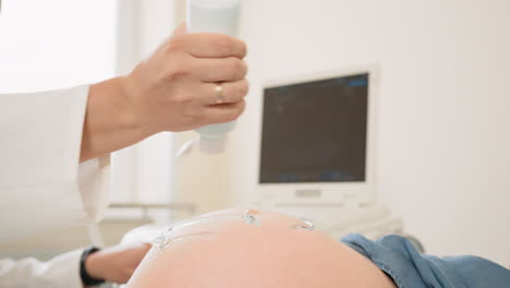 doctor applying gel for ultrasound scan on pregnant woman