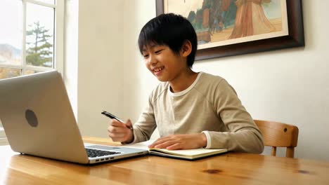 happy young asian boy enjoying online learning with his laptop