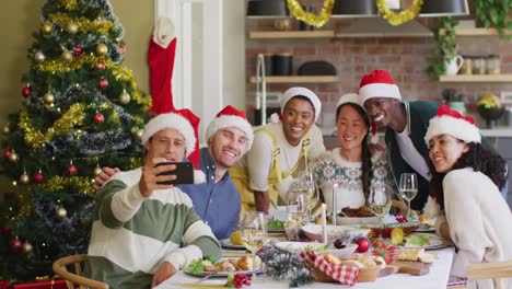 grupo feliz de amigos diversos en sombreros de santa celebrando la comida, tomando selfies en el tiempo de navidad