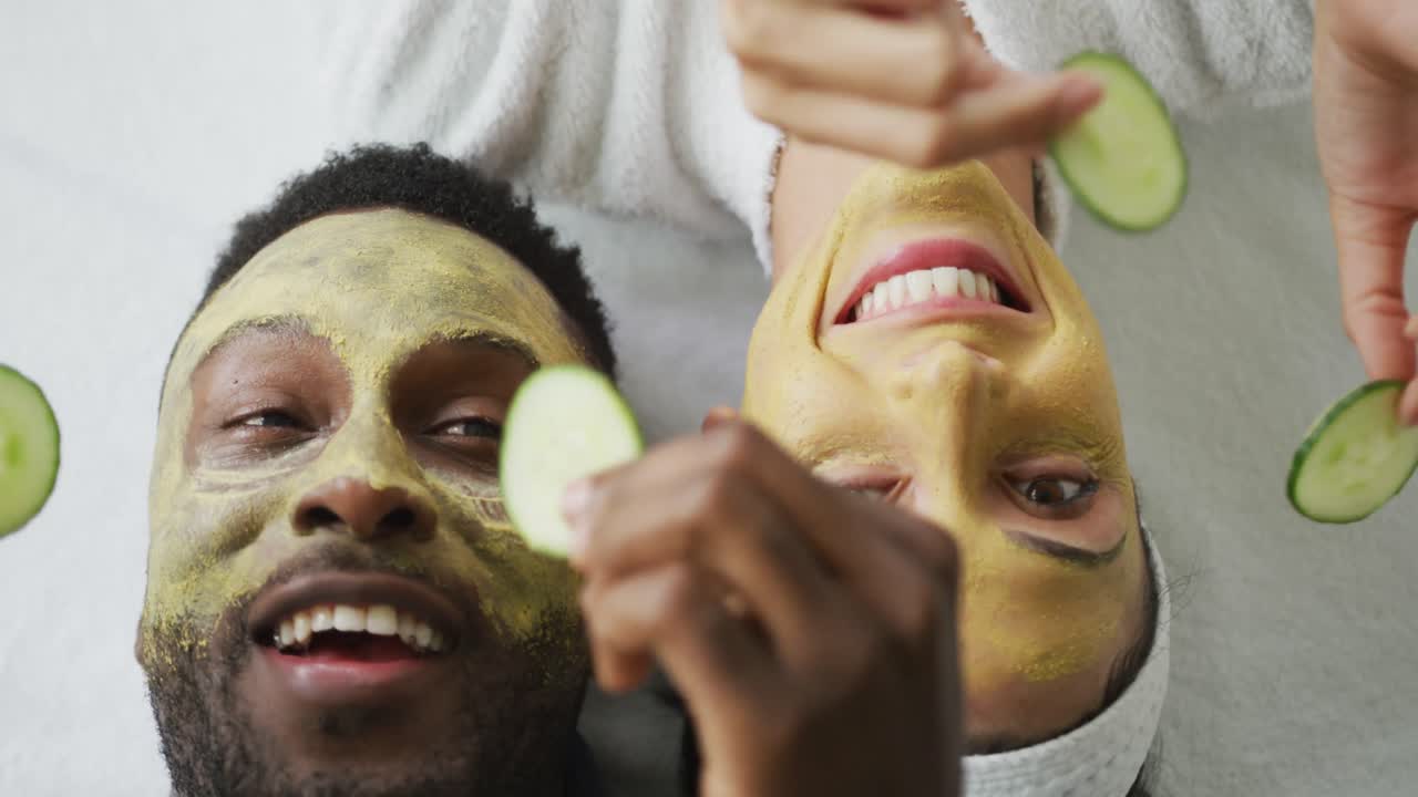 retrato de una feliz pareja diversa acostada con máscaras en el baño