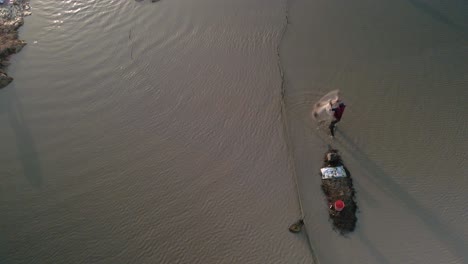 fisherman cast net fishing in tonle sap waterway in asia, aerial birds eye view during late afternoon setting sun, slow-mo copy space