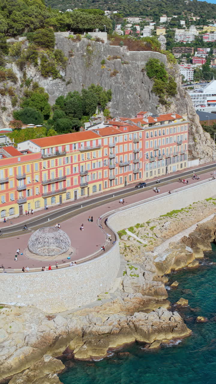 Dronebillede i fugleperspektiv af Castel Plage-stranden og den kurvede kystvej for foden af Castle Hill, Nice. Lodret, Nice, Frankrig
