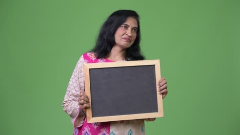 mujer india hermosa madura mostrando la pizarra mientras piensa