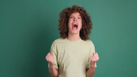 shocked young woman showing stretched hands with palms on green background