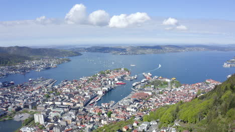 beautiful drone shot of bergen, norway, pulling back from the city and over the mountain